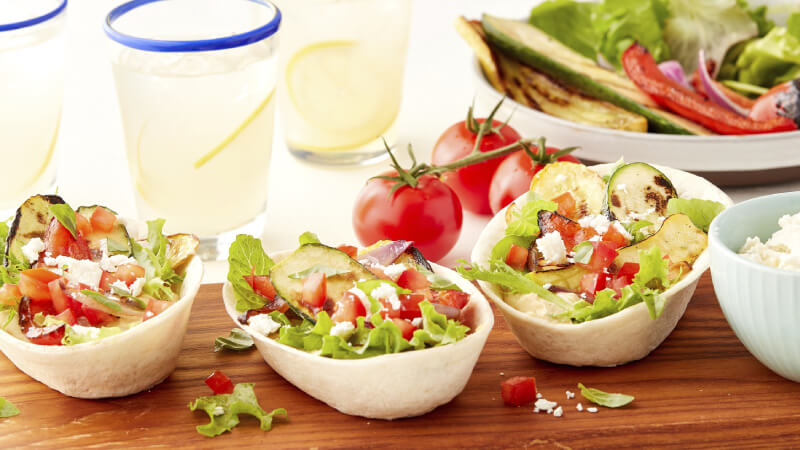Old El Paso Soft Tortilla Bowls filled with a variety of grilled vegetables on a wooden serving board
